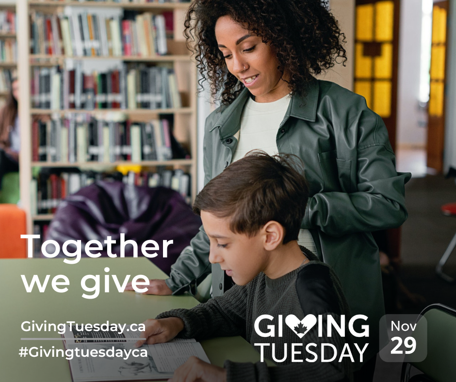 Giving Tuesday boy and adult female at table in library.